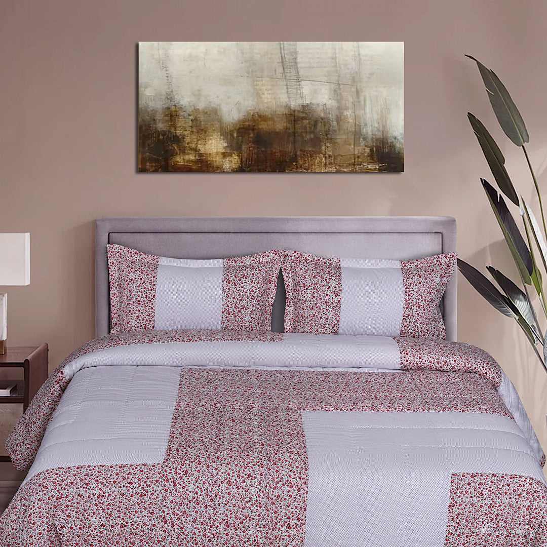 Blush floral patchwork quilt with matching shams styled on a bed